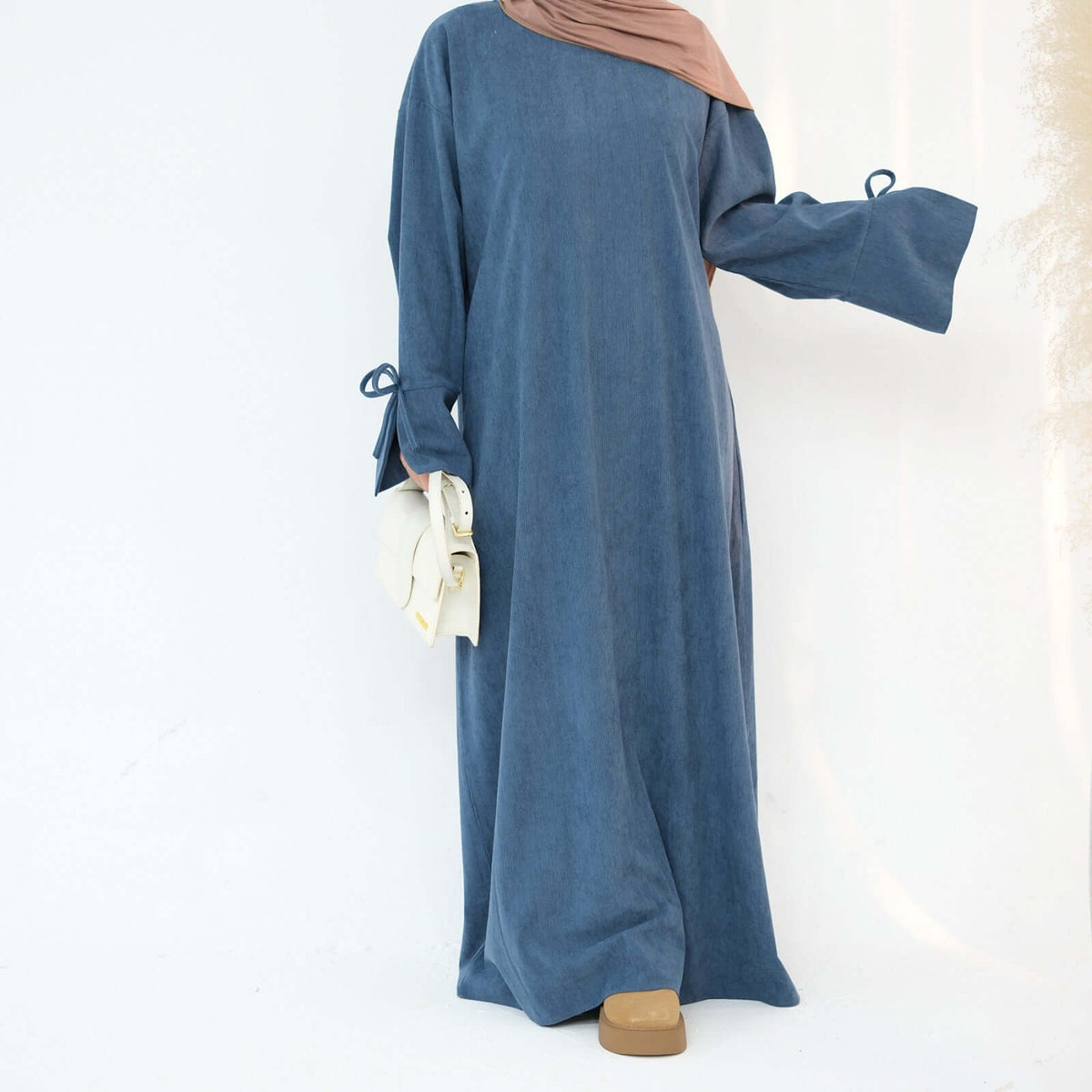 Nawal Corduroy Abaya in soft blue, featuring adjustable tie sleeves and a modern design for everyday elegance.